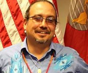 man poses with American flag in background