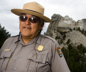 NPS employee in park with Mount Rushmore in the background