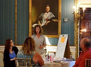 People talk while sitting and standing around a table. People talk while sitting and standing around a table.