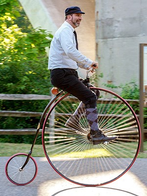 Man riding a bicycle with a large front wheel