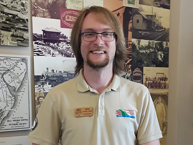 AmeriCorps member Ben Duvall-Irwin stands in front of an exhibit at Elkins Depot Welcome Center
