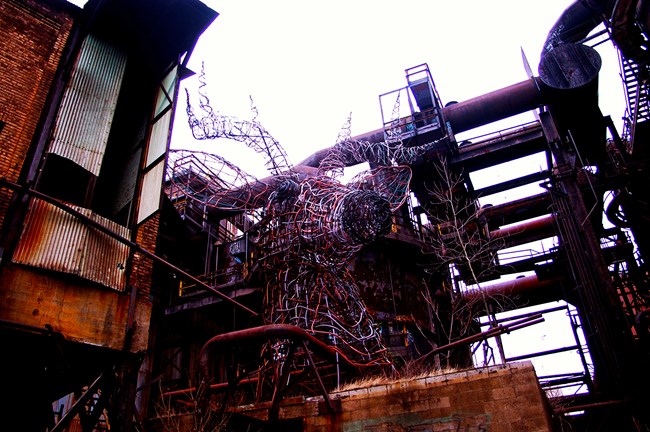 The metal sculpture of a deer head, made of wire tubing and pipes.