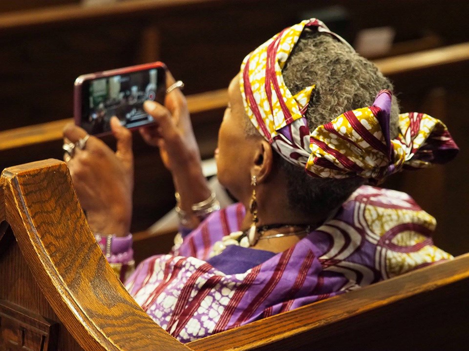 Woman in audience recording Watch Night performance with her phone, Morris Brown AME Church, Charleston, SC, 2018