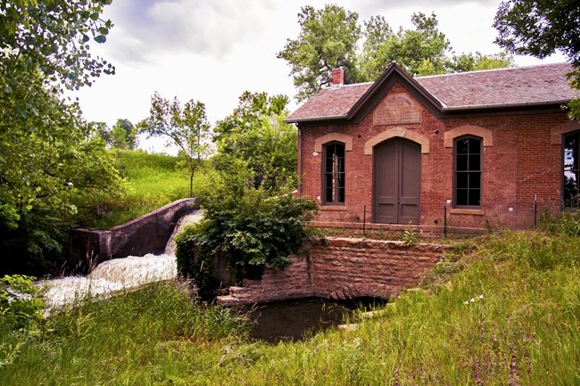 Red brick waterworks surrounded by lush greenery