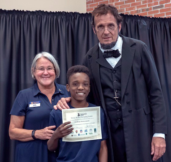 LEAD Emerging Leader LEAD youth participant holding a certificate presented to him by Abraham Lincoln reenactor