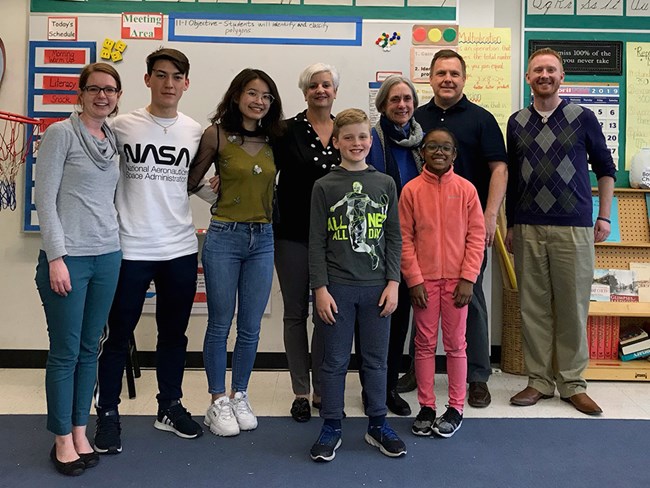 Medford Slavery Memorial Project (Courtesy of Wicked Local/Joseph Lim) A group of nine adults and children stand and smile in a classroom
