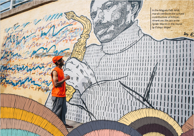 A man paints a detailed mural of a large man with a saxophone
