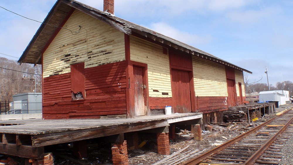 Old red and white wooden building next to railroad tracks