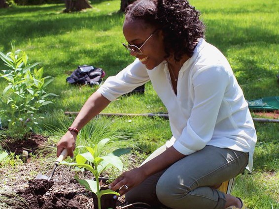 Young woman uses a trowel while working in the Pottstown Riverfront Park pollinator garden