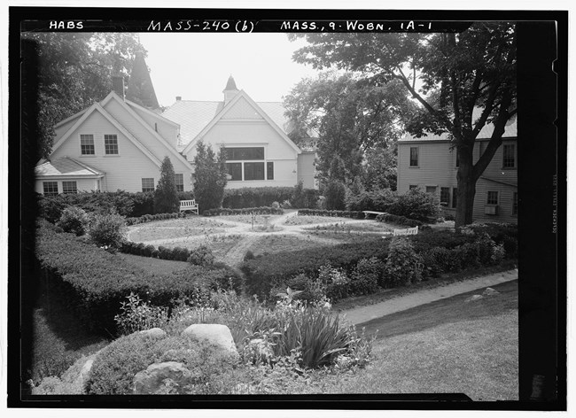 lt= Greyscale photograph of wheel shaped garden lawn in front of house
