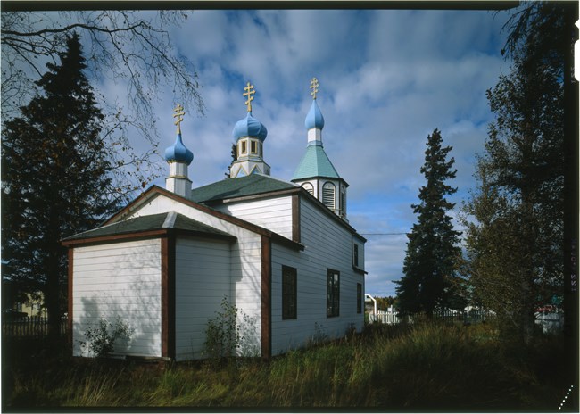 White wooden church with three blue onion domes