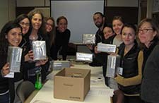 Ten people face the camera, each person smiles while holds a tightly wrapped silver package