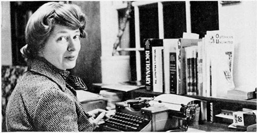 Dorothy Huyck sitting at a desk in front of a typewriter, looking towards the camera.