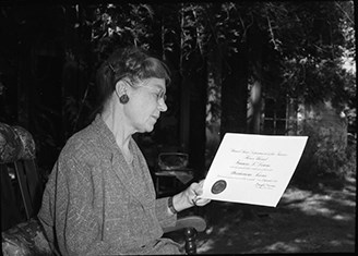 Frances L. Downs look down at the award certificate held in her left hand.