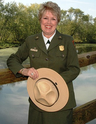 Mary A. Bomar stands smiling in her NPS uniform, holding her wide-brimmed hat in her hands.