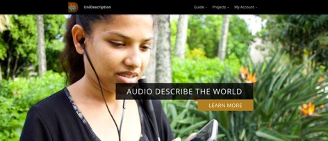 A woman wears headphones that are attached to a mobile device she is holding.  There is lush flora behind her.