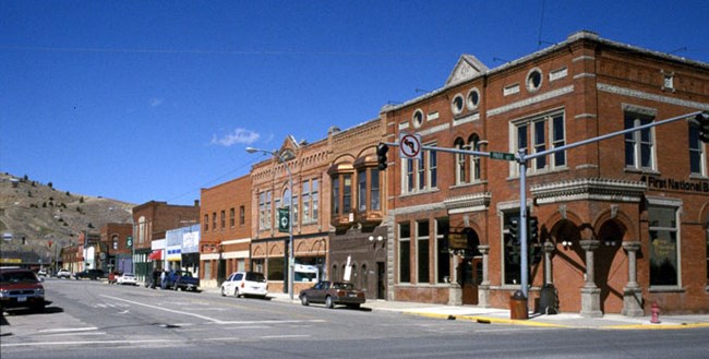 Downtown Anaconda, Montana showing a row of low brick buildings against a blue cloudless sky.