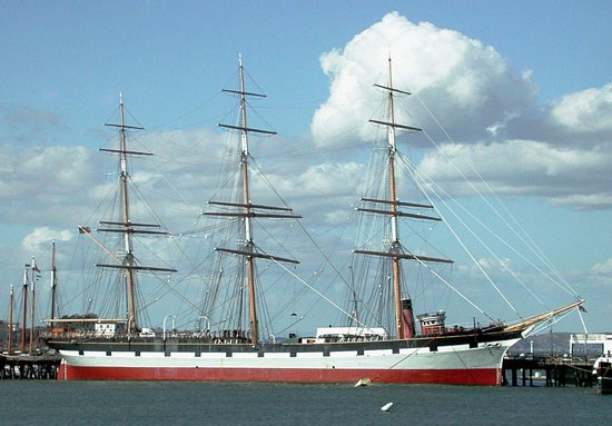 A three-masted ship at dock.
