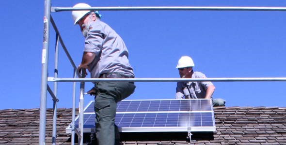 men installing solar panels on a roof