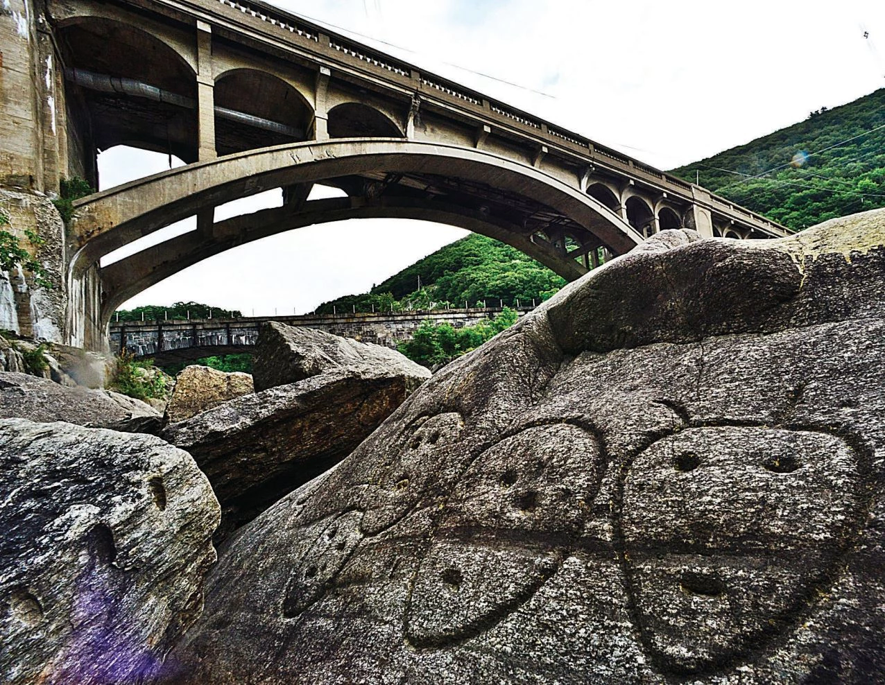 Bellows Falls Petroglyphs (Rockingham, VT) Rocks with carvings on them in foreground; bridge in background