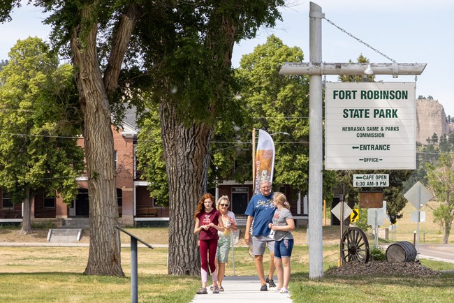 Group of people on sidewalk by sign reading "Fort Robinson State Park Nebraska Game & Parks Commission."