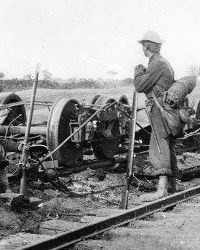 Photo of Soldier looking at destroyed railroad car.