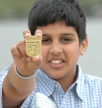 Kid holding up a Junior Ranger badge
