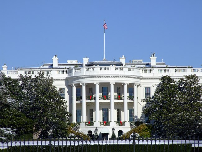 South view of the White House framed by trees.