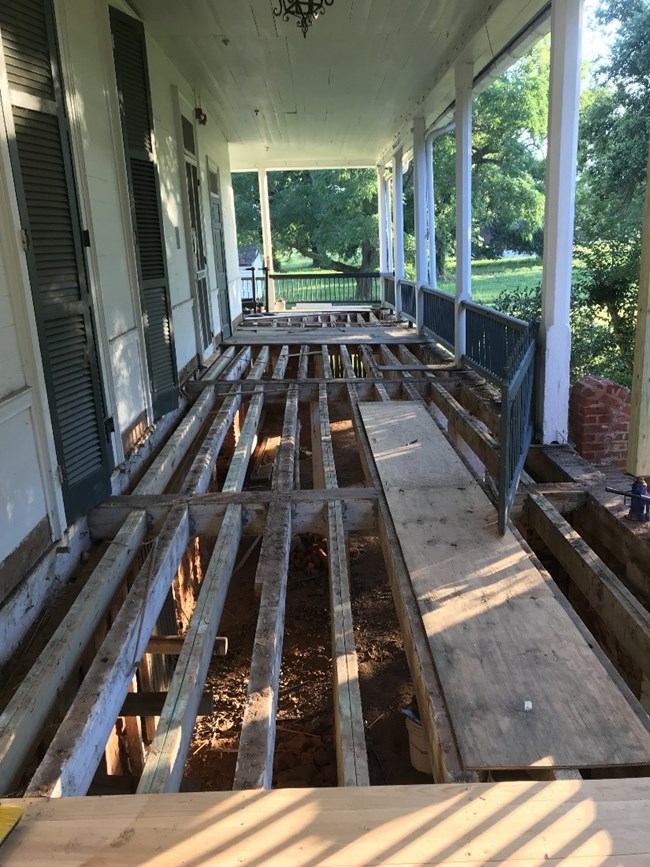 Wrap-around porch with exposed beams. Underlying structure is aged and shows signs of damage. Wrap-around porch with exposed beams. Underlying structure is aged and shows signs of damage.