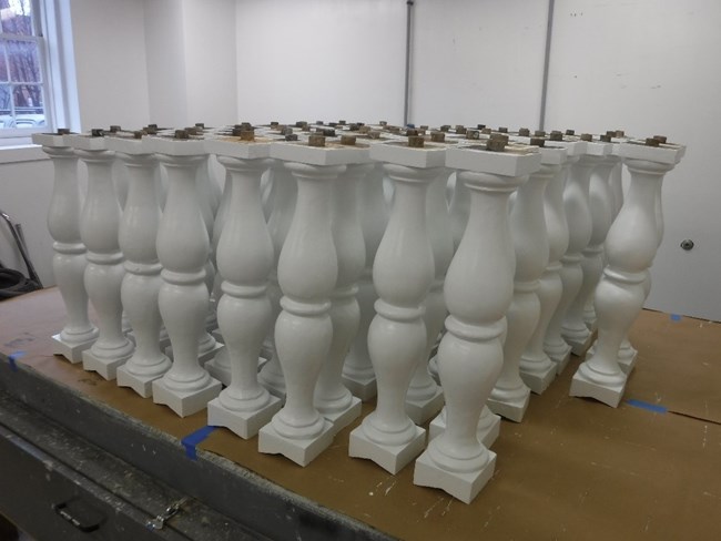 Freshly painted wooden balusters are propped up to dry on a work table Freshly painted wooden balusters are propped up to dry on a work table