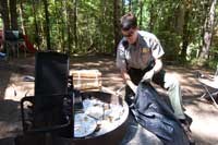a ranger cleans a fire pit of trash