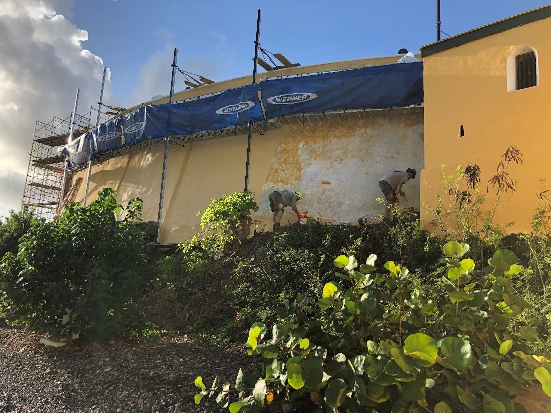 Workers repair damaged stucco wall under the sun Workers repair damaged stucco wall under the sun