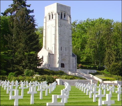 The Aisne_Marne American Cemetery Rows of white crosses stand in front of a tower, which is bordered by trees.