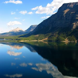 A mountain in Glacier National Park is reflected in a still lake.