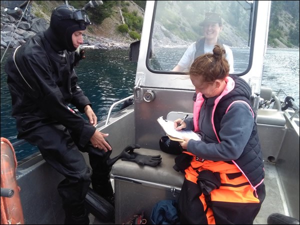 Asuncion records scientific data. An international volunteer records scientific data while sitting in a small boat at Crater Lake National Park.