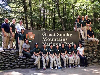 lt= Staff from Great Smoky Mountains National Park and counterparts from Thailand stand in front of the park sign.