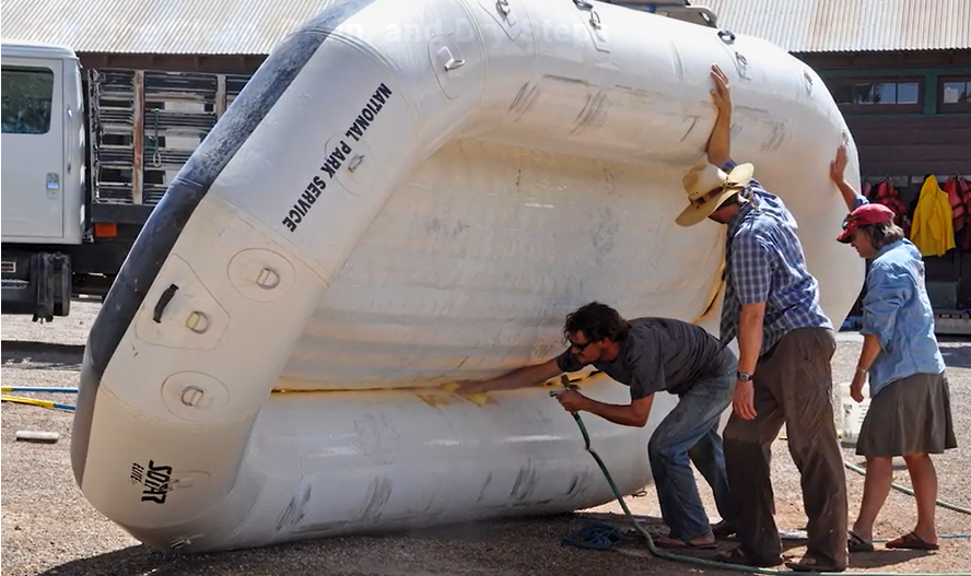Three people clean, drain, and dry an inflatable raft