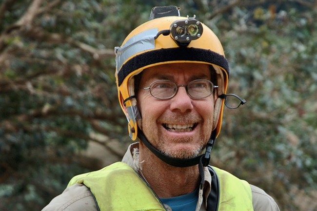 Man with life jacket and helmet with headlamp.