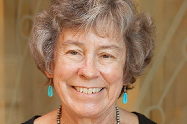 Woman with black shirt, necklace, and short hair.