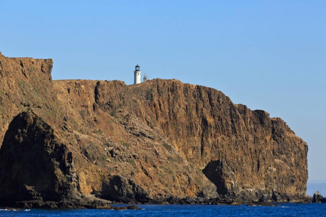 brown rocky cliffs of Anacapa Island with view of lighthouse on top of them