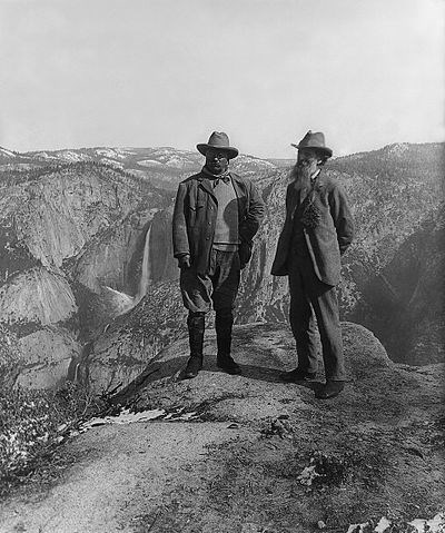 Historic photo of two men on granite peak overlooking large waterfall