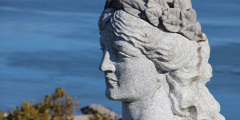 YorktownVictory A granite head of a victory, a woman with hair pulled up encircled with a wreath, overlooks blue water.