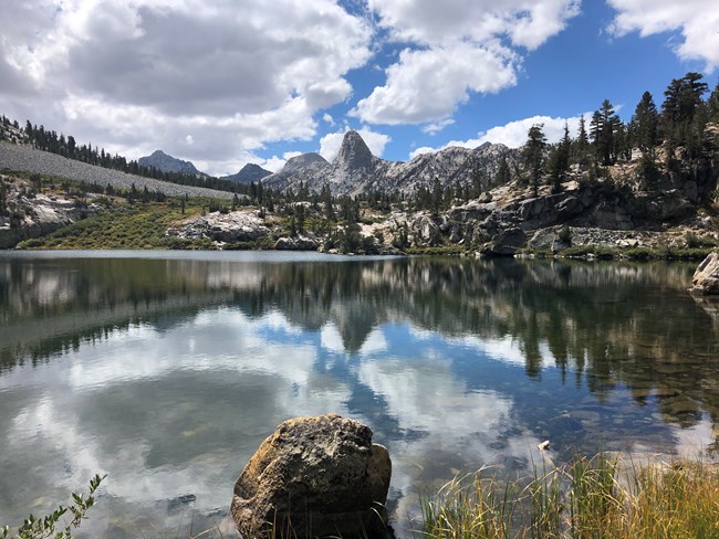 Distant granite dome and clouds reflected in mountain lake