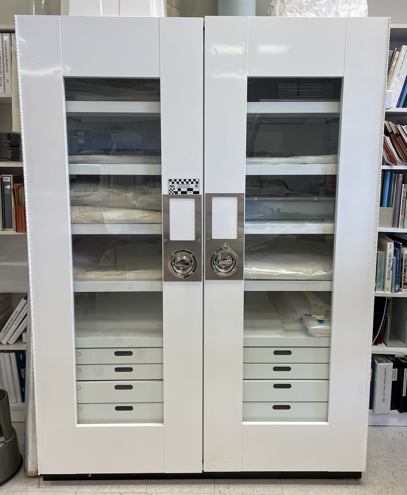 A white metal cabinet with two doors, each with glass panes in them.