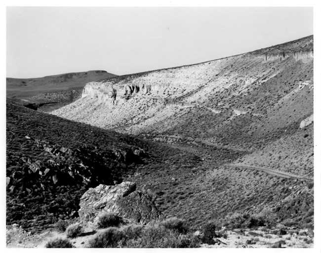 wagon trail line between two grassy hills