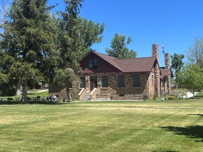 View of stone building across grassy lawn with mature trees