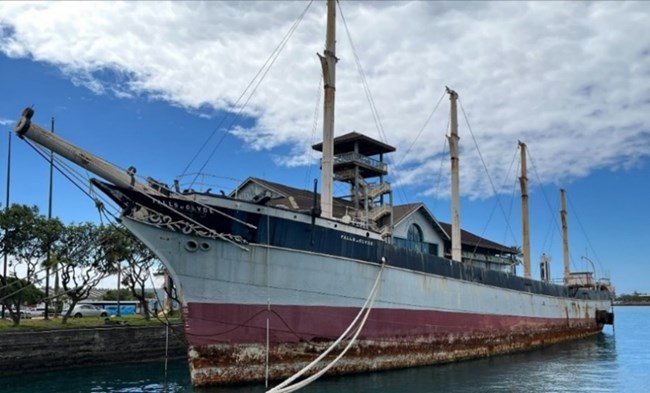 Ship docked at harbor showing severe hull deterioration