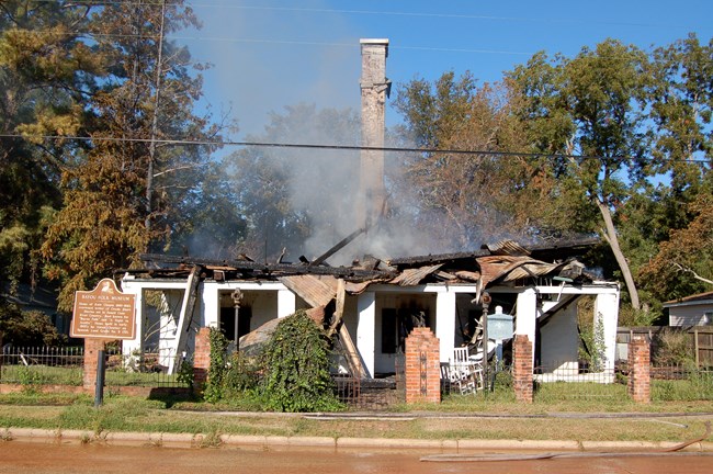 smoldering house with smoke billowing from burned remains