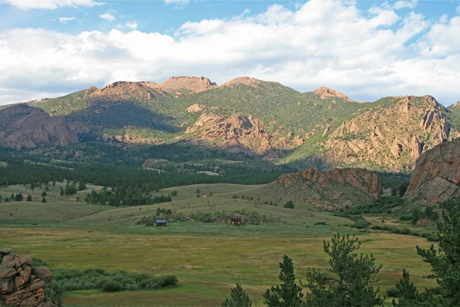 Open area with mountains in the background and two small buildings in center