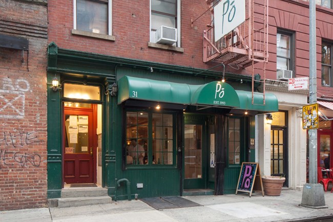 Small storefront on street with Green awning